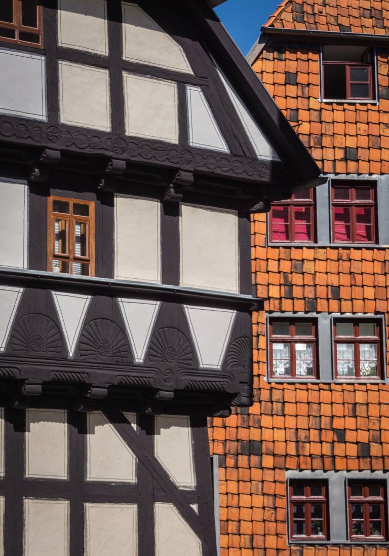 Fachwerkhaus mit schwarzem Holzrahmen und orangefarbenen Schindeln im Hintergrund.